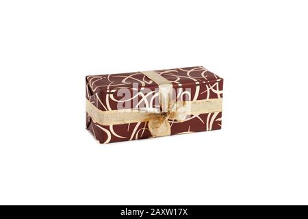 packaged rectangular gift in dark brown packaging with gold bow and gold pattern on a white background Stock Photo