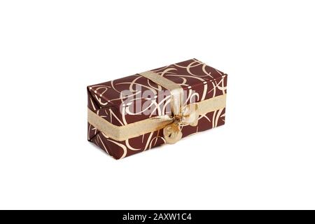 packaged rectangular gift in dark brown packaging with gold bow and gold pattern on a white background Stock Photo
