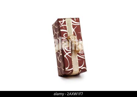 packaged rectangular gift in dark brown packaging with gold bow and gold pattern on a white background Stock Photo