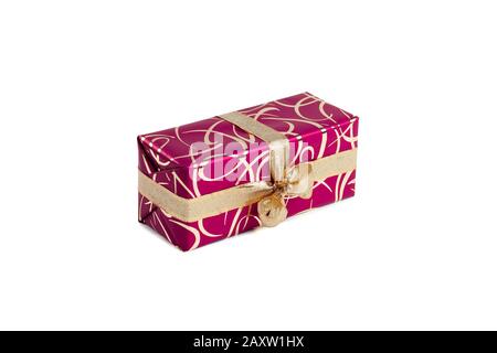 packaged rectangular gift in dark pink packaging with gold bow and gold pattern on a white background Stock Photo