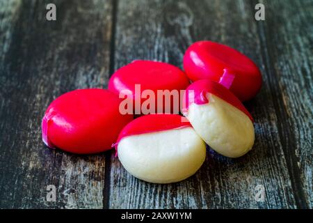 Babybel Cheese in Red Wex on Wooden Surface Ready to Eat. Instant Food. Stock Photo