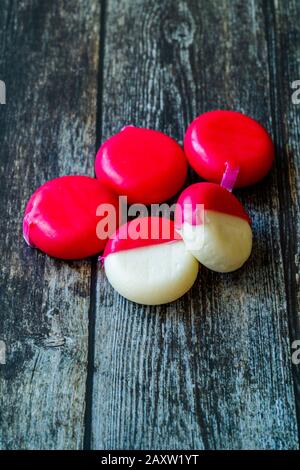 Babybel Cheese in Red Wex on Wooden Surface Ready to Eat. Instant Food. Stock Photo