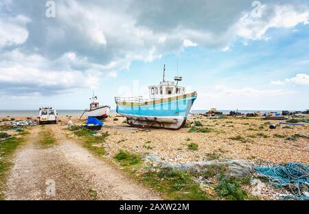 Old fishing boats hauled up and beached on the shingle beach at Dungeness, Shepway district, Kent on a sunny spring day Stock Photo