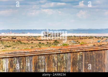 Decaying hull of an old wooden fishing boat abandoned on the shingle beach at Dungeness, Shepway district, Kent on a sunny spring day Stock Photo