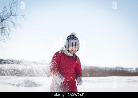 Children have fun throwing snow. The girl is warmly dressed, throws snow on a frosty sunny day. Stock Photo