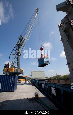 Liebherr Crane loading containers into cargo ship. Unloading from the belly of  a container ship Stock Photo