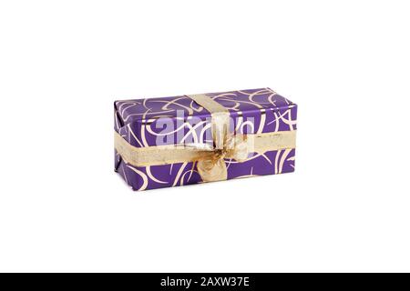 packaged rectangular gift in purple packaging with gold bow and gold pattern on a white background Stock Photo