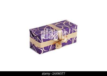 packaged rectangular gift in purple packaging with gold bow and gold pattern on a white background Stock Photo
