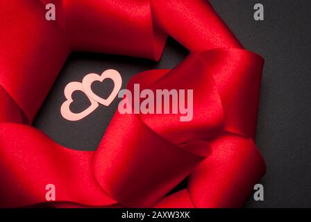 Pair of two open hearts shining together in the shadows of luxurious red satin ribbon Stock Photo