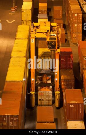 Container movers moving containers around port terminal for loading on and off ship. Stock Photo