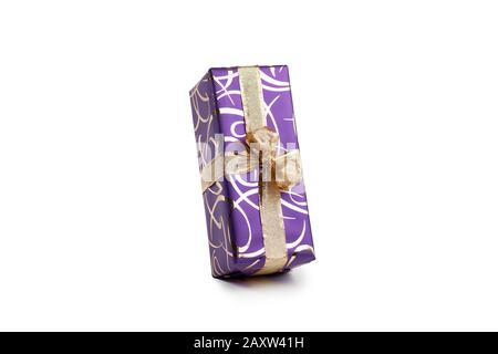 packaged rectangular gift in purple packaging with gold bow and gold pattern on a white background Stock Photo