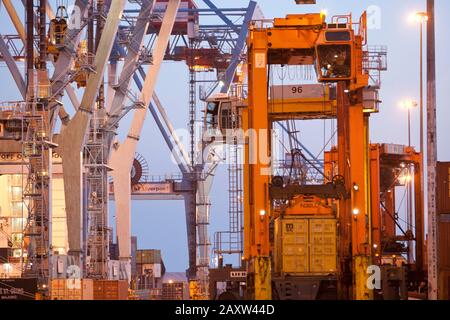 Container movers moving containers around port terminal for loading on and off ship. Stock Photo