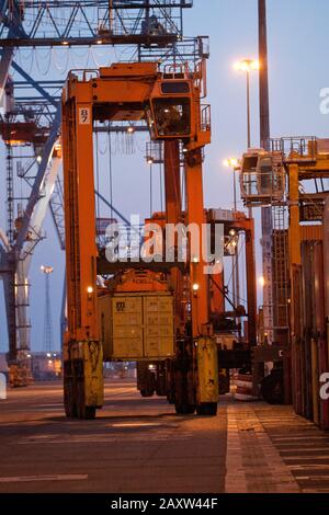 Container movers moving containers around port terminal for loading on and off ship. Stock Photo