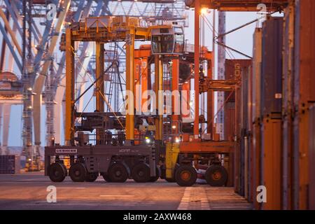 Container movers moving containers around port terminal for loading on and off ship. Stock Photo