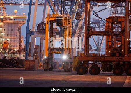 Container movers moving containers around port terminal for loading on and off ship. Stock Photo