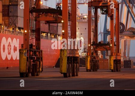 Container movers moving containers around port terminal for loading on and off ship. Stock Photo