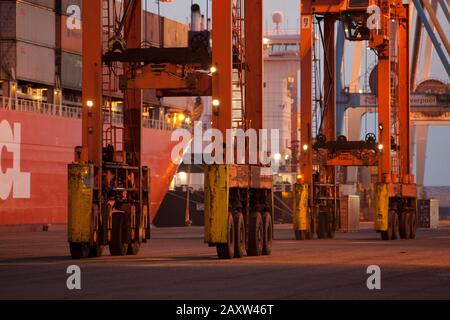 Container movers moving containers around port terminal for loading on and off ship. Stock Photo