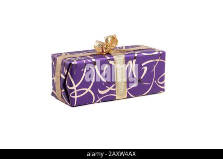 packaged rectangular gift in purple packaging with gold bow and gold pattern on a white background Stock Photo