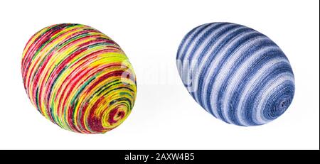 Two colorful streaked Easter eggs hand-decorated by glued thin cotton yarn or painted twine. Original ornate holiday decoration from chicken eggshells. Stock Photo