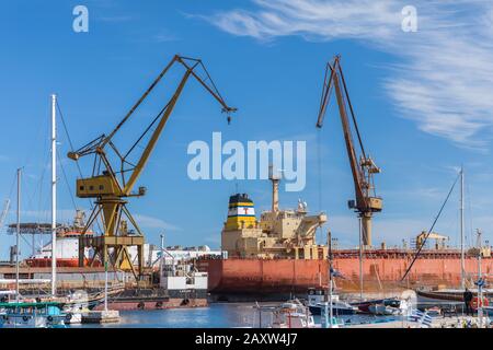 Ermoupolis: February 13th . Two big industrial cranes working on a ship in Neorion Shipyard in Syros. Syros: February 13th, 2020, Greece. Stock Photo