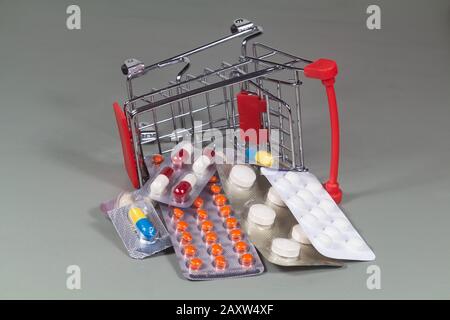 Small shopping cart overturned and pack of pills Stock Photo