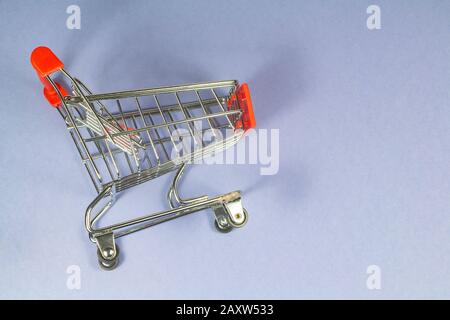 Small metal shopping cart on blue background Stock Photo