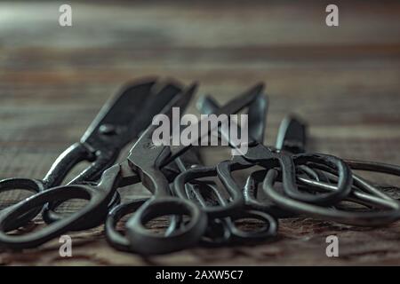 Vintage steel scissors on wooden table background. Old-fashioned instruments for florist, barber, seamstress. History, professional collection of equipment, beauty of workplace. Vintage, retro style. Stock Photo