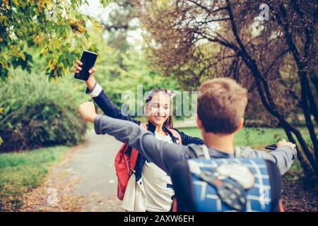 Two school friends hugging, emotional meeting in the park. Walking into each other with open arms and smiling. The concept of school, study, education Stock Photo
