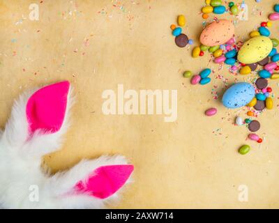 Cute creative composition with multi colored easter eggs, colorful sweets, and bunny ears. Easter and Springtime concept Stock Photo