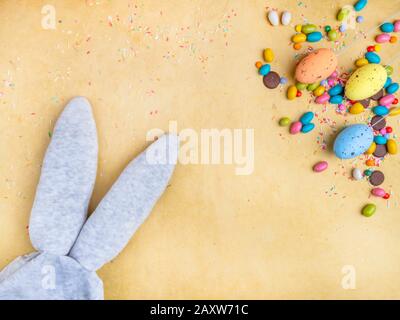 Cute creative composition with multi colored easter eggs, colorful sweets, and bunny ears. Easter and Springtime concept Stock Photo