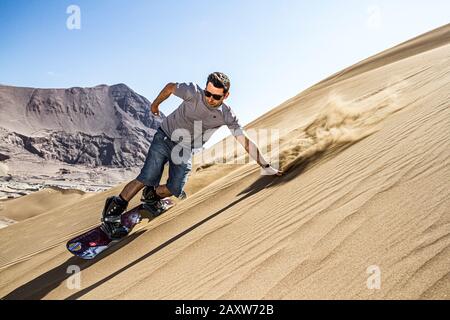 Sandboarding in Cerro Dragon, in Atacama Desert. Iquique, Tarapaca Region, Chile. Stock Photo