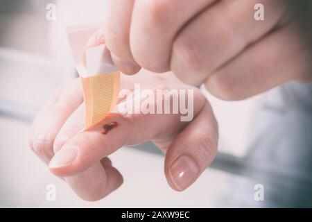 Applying adhesive bandage on bleeding finger Stock Photo