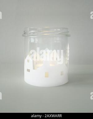 Glass jar used as a lantern with landscape decorations made of white paper Stock Photo