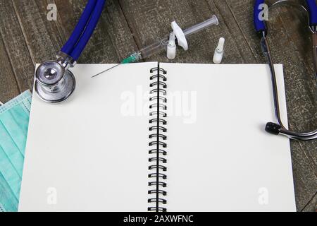 Background for medical subjects with copy space: View on open ringe file with white blank pages, stethoscope, syringe, vials Stock Photo