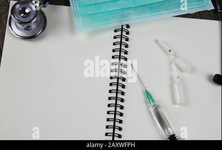 Background for medical subjects with copy space: View on open ringe file with white blank pages, stethoscope, syringe, vials Stock Photo