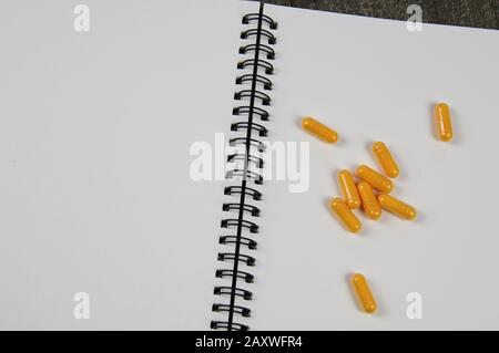 Background for medical subjects with copy space for text: View on open ringe file with white blank pages and group of yellow pills Stock Photo