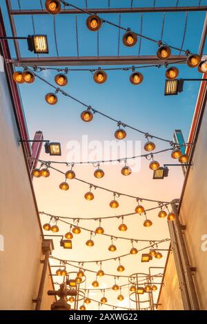 Modern light bulbs lighting on the background of the sunset sky on the street of the city Stock Photo