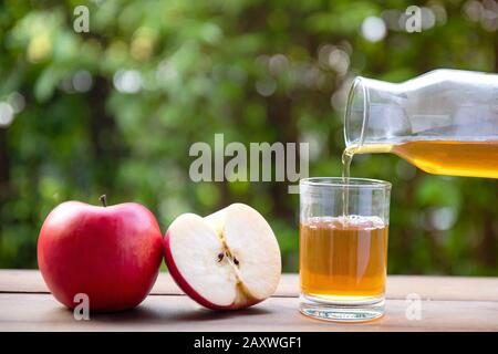 Apple juice pouring from red apples fruits on wood Floor and Bokeh Background Stock Photo