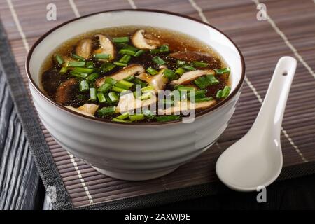 Asian soup with shiitake mushrooms and green onions close-up in a bowl on the table. horizontal Stock Photo