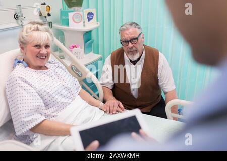 Doctor with digital tablet talking with senior couple in hospital room Stock Photo