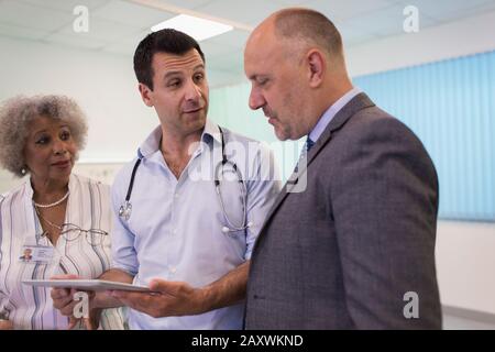 Doctors with digital tablet making rounds, consulting in hospital Stock Photo