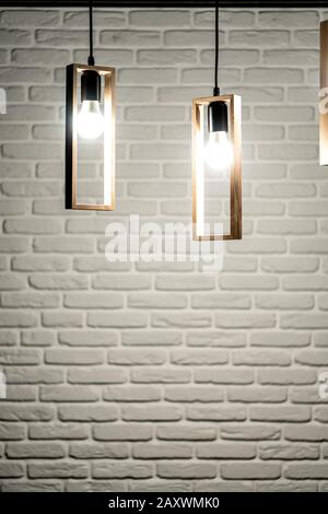 Three lamps on a background of a white brick wall. Three light bulbs on a white brick background. White brick background with three swirls that hang Stock Photo