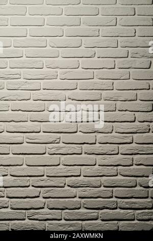White brick wall of a warm shade lit from above by a lamp. White brick wall, perfect as a background, square photograph. The brick background is white Stock Photo