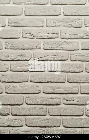 White brick wall of a warm shade lit from above by a lamp. White brick wall, perfect as a background, square photograph. The brick background is white Stock Photo