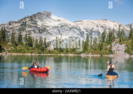Mother and daughter enjoy boating on beautiful blue alpine lake Stock Photo