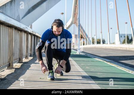 Young man tying laces of running shoes before training,closeup on shoe. Stock Photo