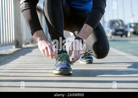 Young man tying laces of running shoes before training,closeup on shoe. Stock Photo