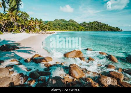 Mahe, Seychelles. Beautiful Anse intendance, tropical beach with ocean wave rolling towards sandy beach. Coconut palm trees on shore in background Stock Photo