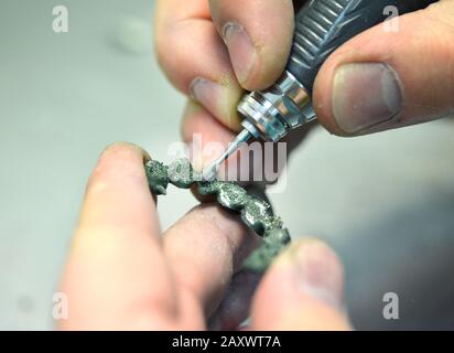 Dentist hand mills tooth crowns created on 3d printer for metal. Dental technician working with ceramic crowns in dental laboratory Stock Photo