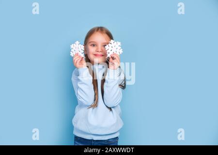 Little girl playing with christmas tree snowflakes on blue background Stock Photo